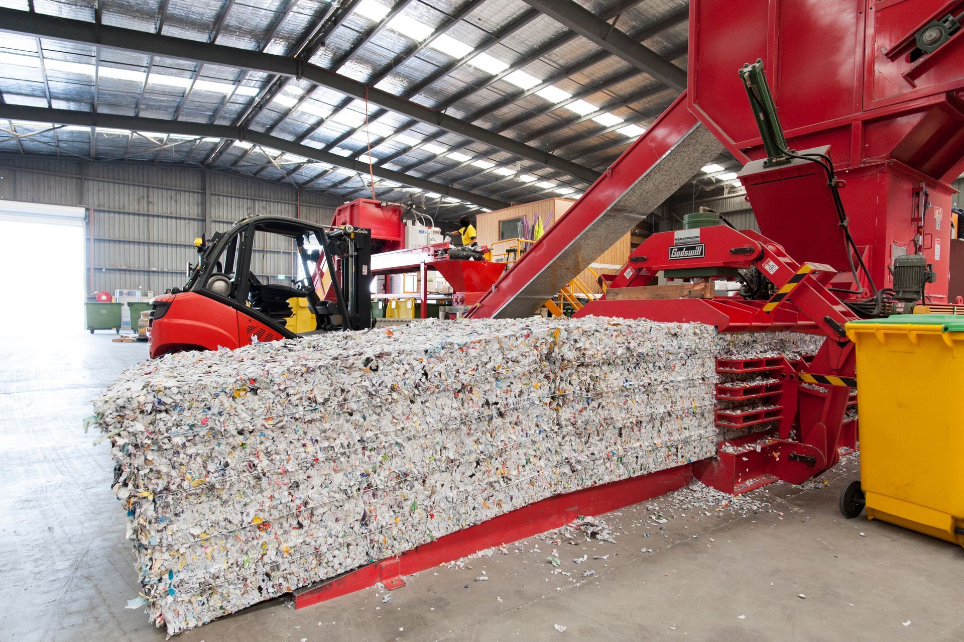 Paper recycling baler compressing shredded confidential documents after secure document destruction.
