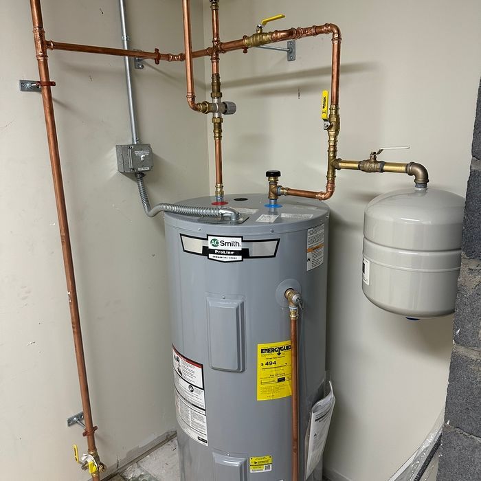 Water heater and copper piping in a utility closet, with a white expansion tank beside it.