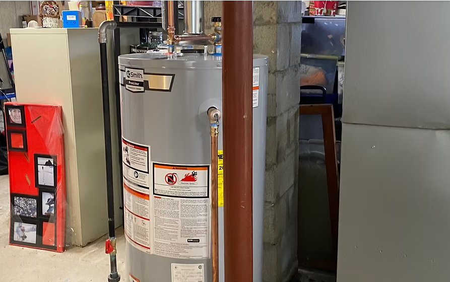 Water heater in a utility room beside cardboard boxes and metal ducting.