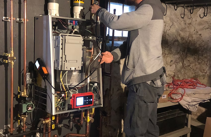 Technician working on an open HVAC unit with tools in a basement utility room