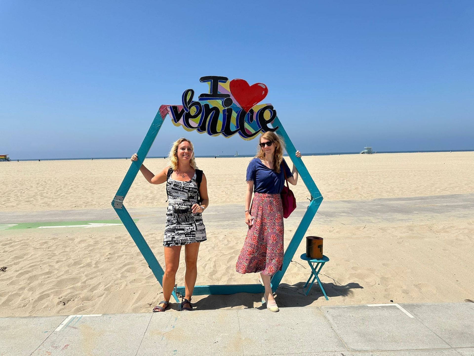 Two women standing in front of a sign that says i love venice