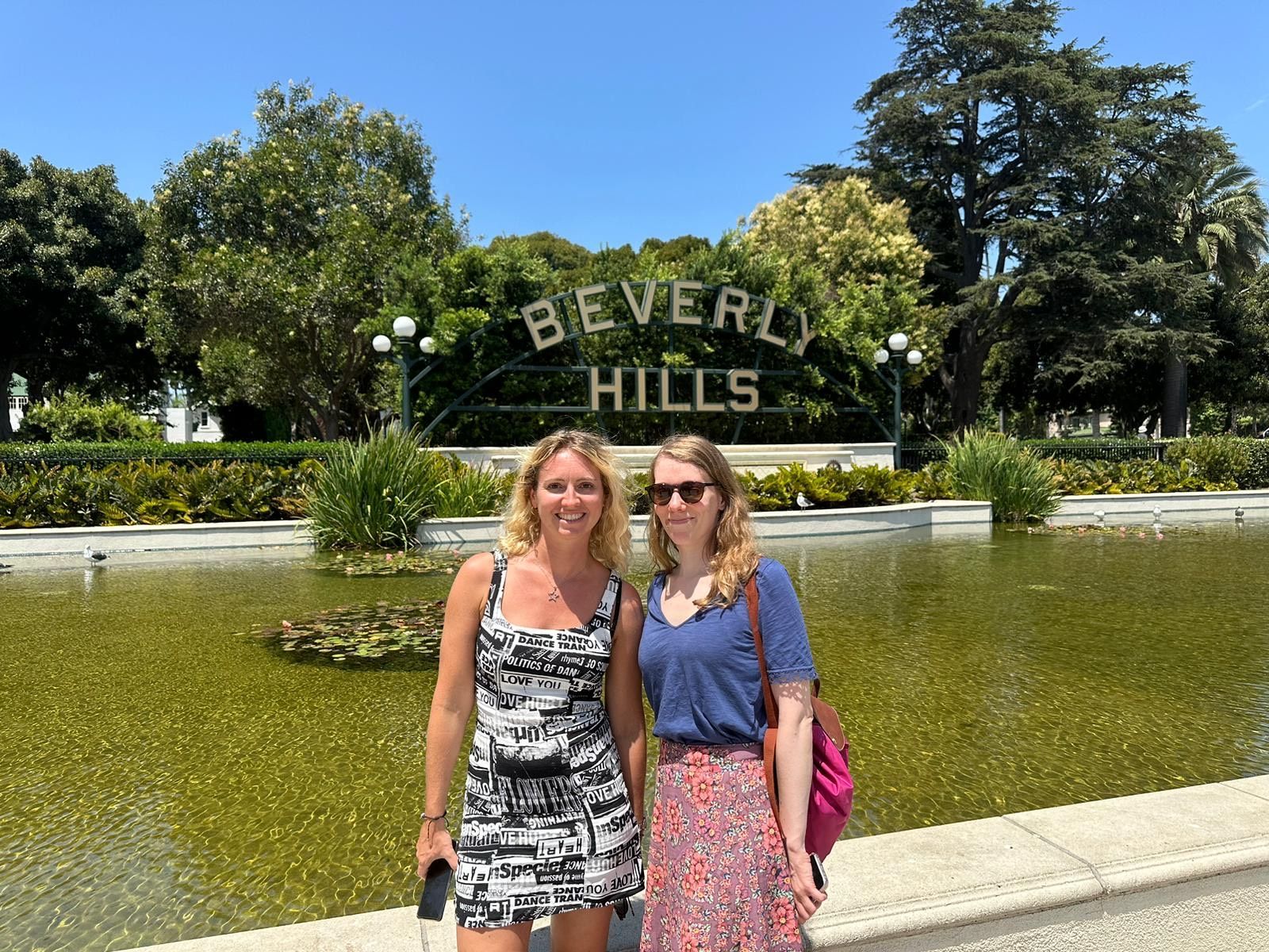 Two women are standing in front of a sign that says beverly hills
