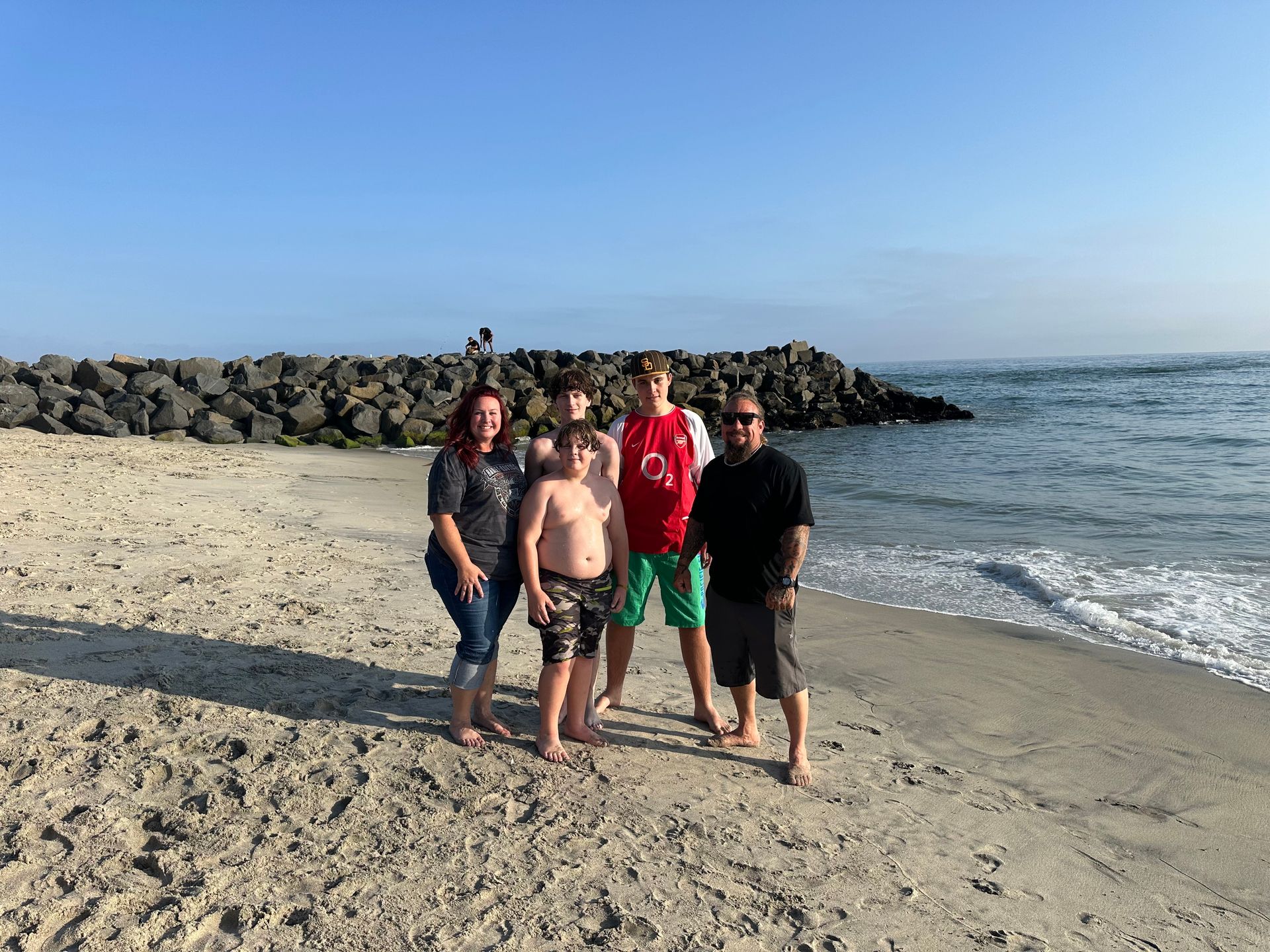 A family is posing for a picture on the beach.
