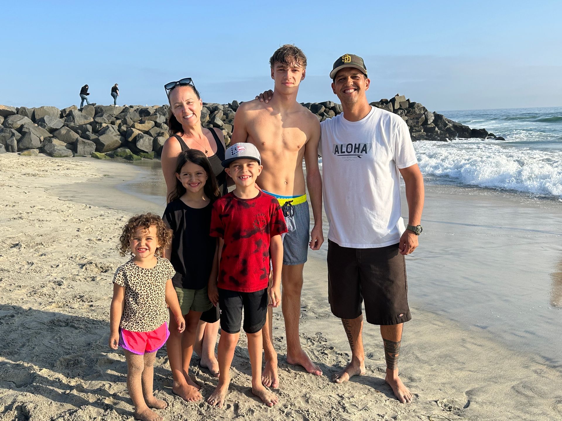 A family is posing for a picture on the beach.
