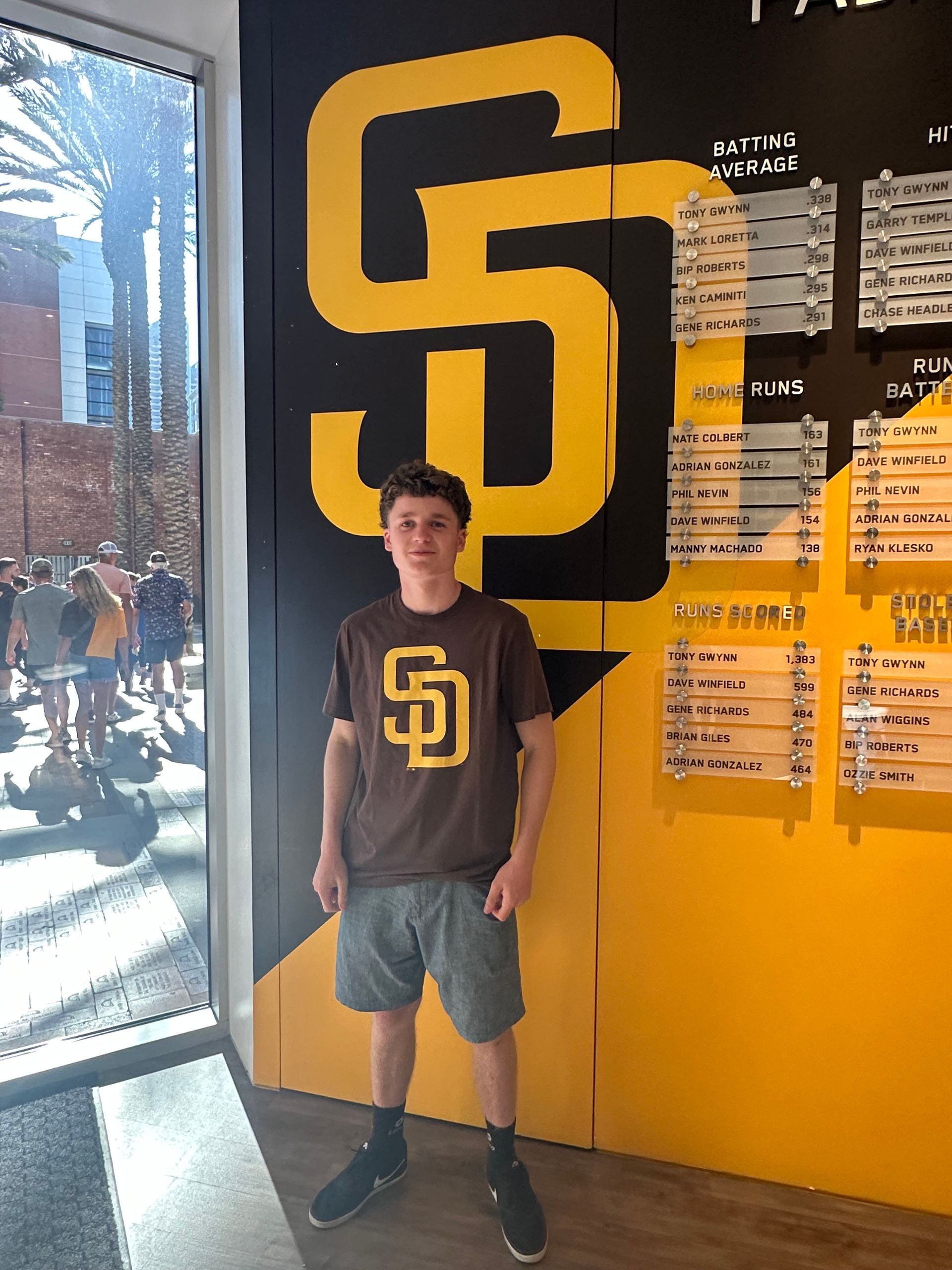 A boy in a san diego padres shirt stands in front of a wall