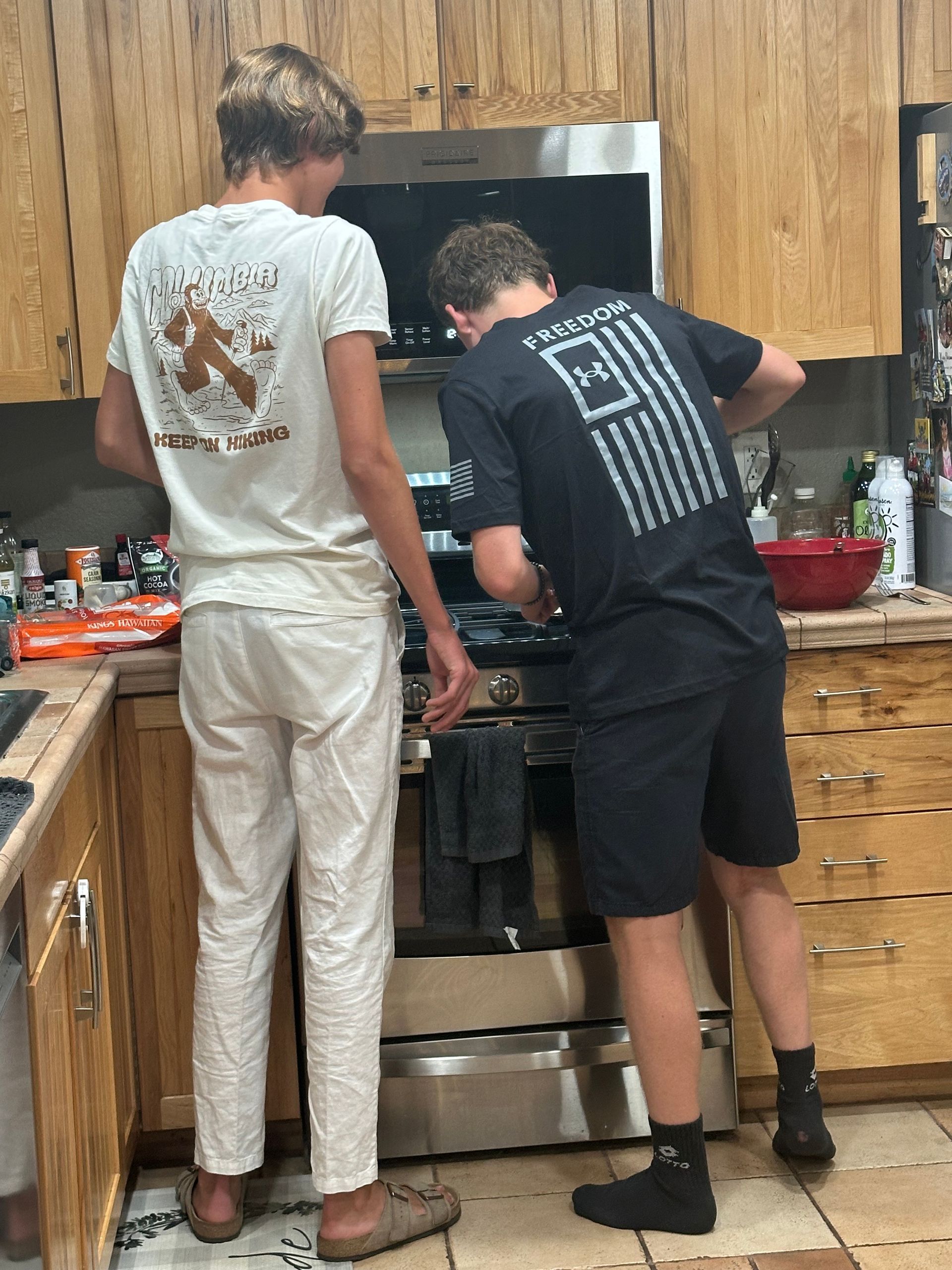 Two young men are standing in a kitchen preparing food.