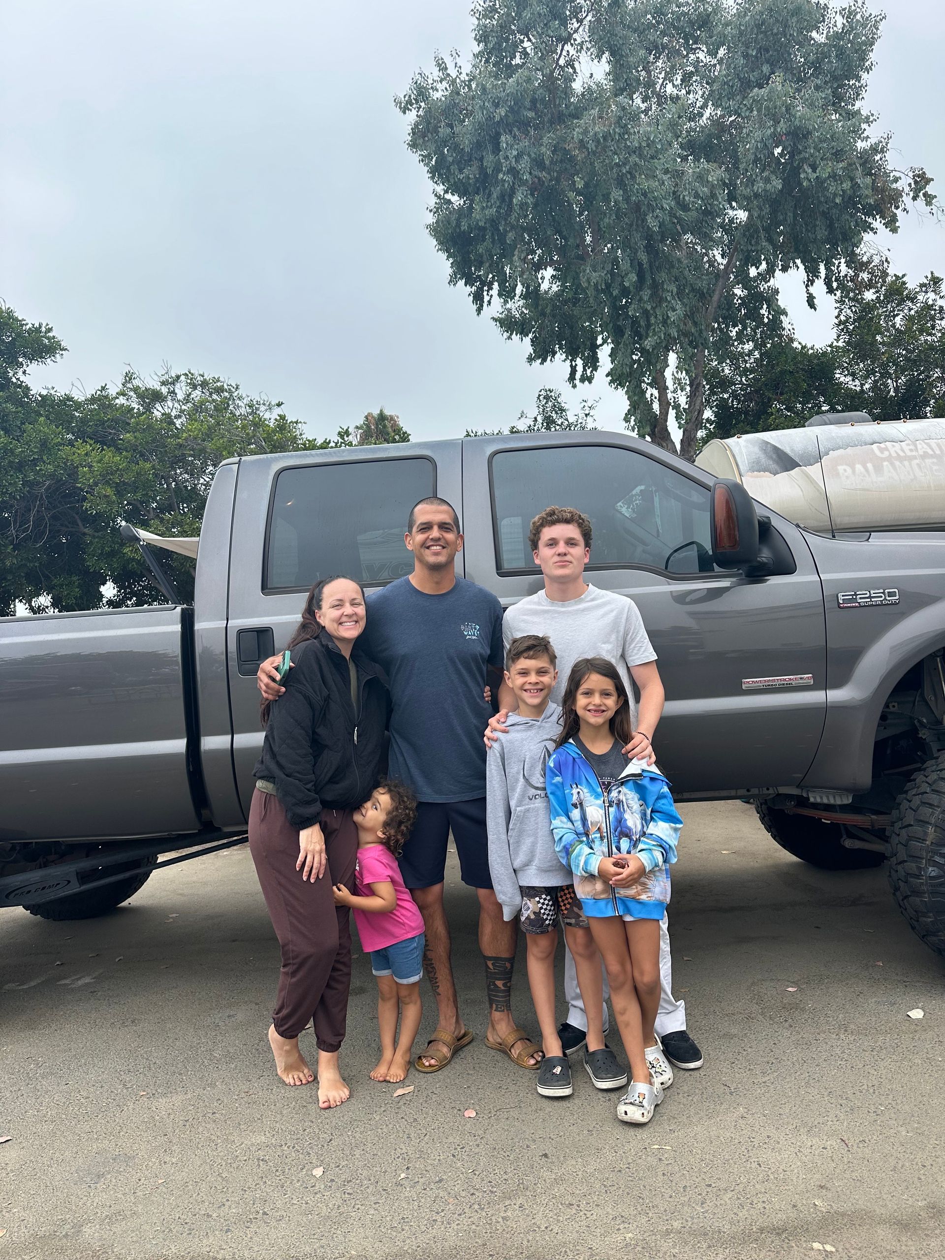 A family is posing for a picture in front of a truck.
