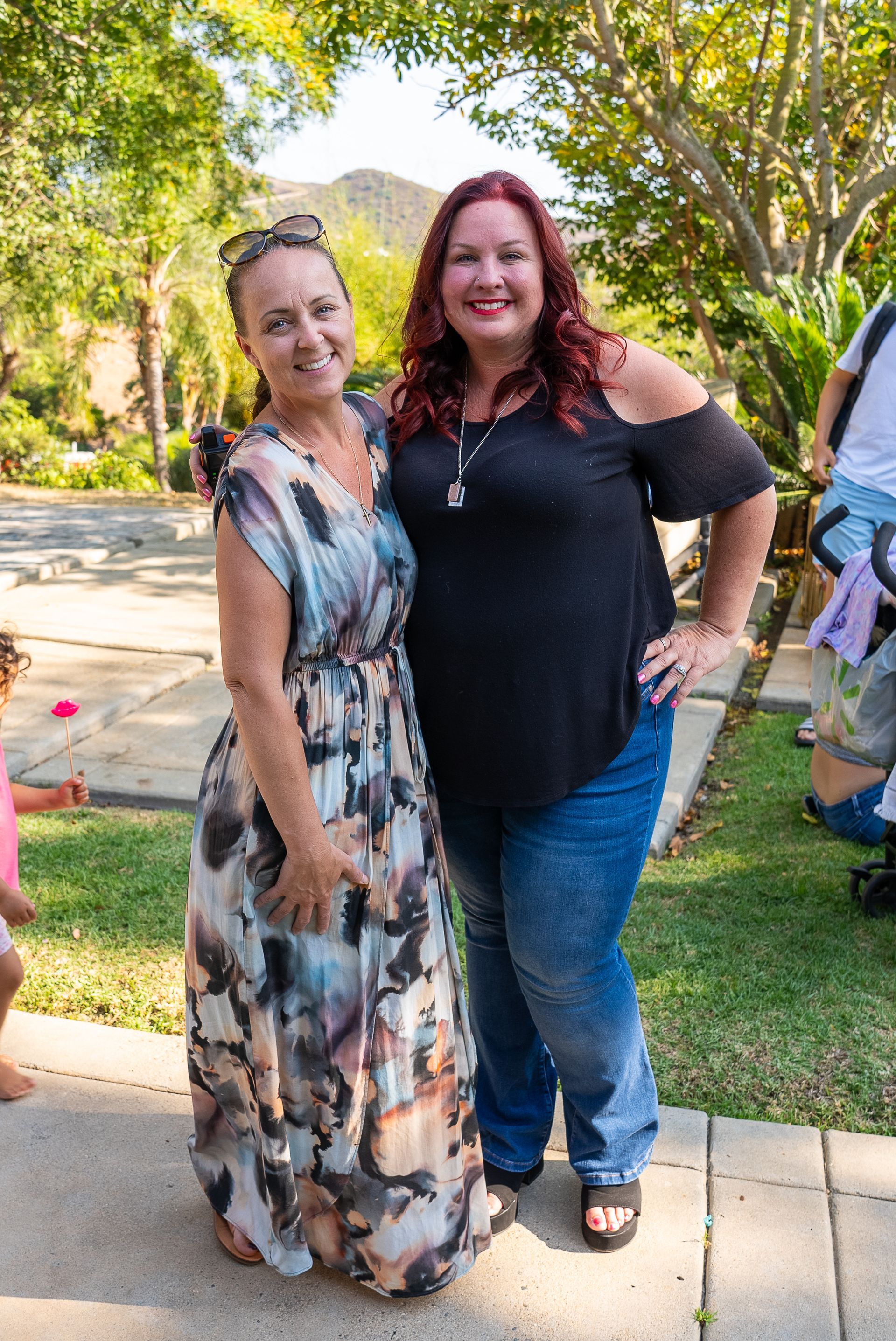 Two women are posing for a picture together in a park.