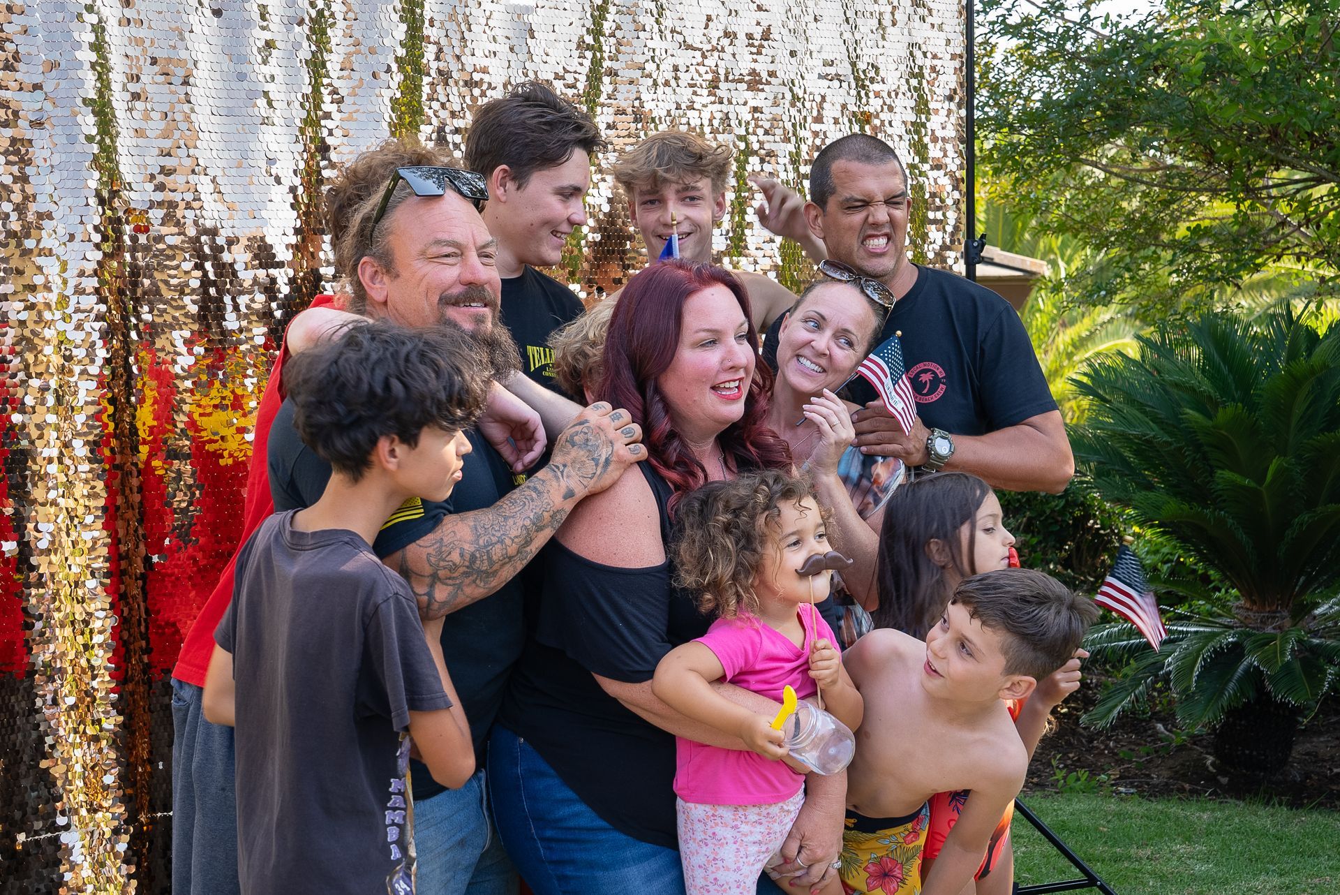 A large family is posing for a picture in front of a sequined backdrop.