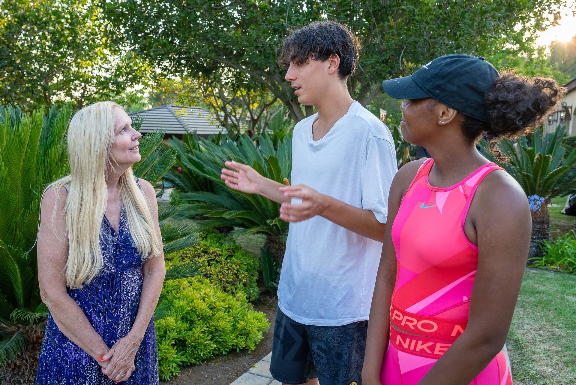 A group of people are standing next to each other in a park talking to each other.