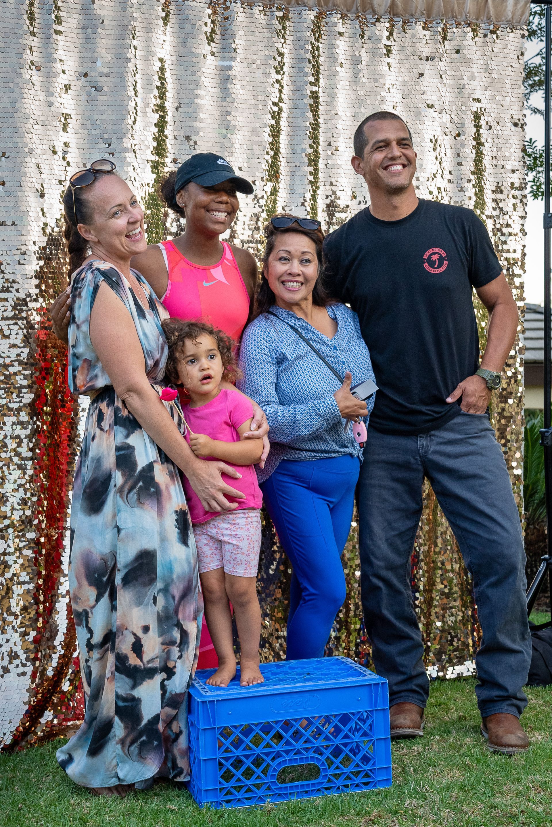 A group of people are posing for a picture in front of a sequined wall.