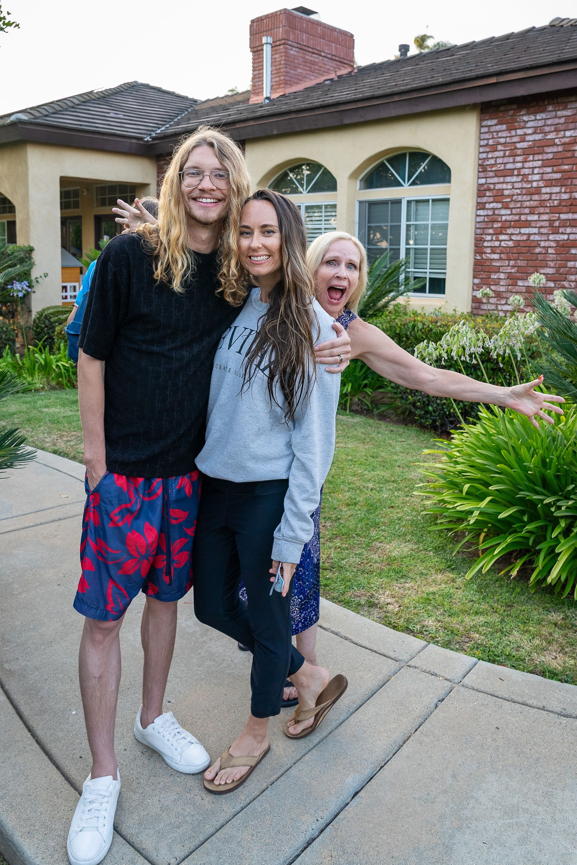 A group of people are posing for a picture in front of a house.