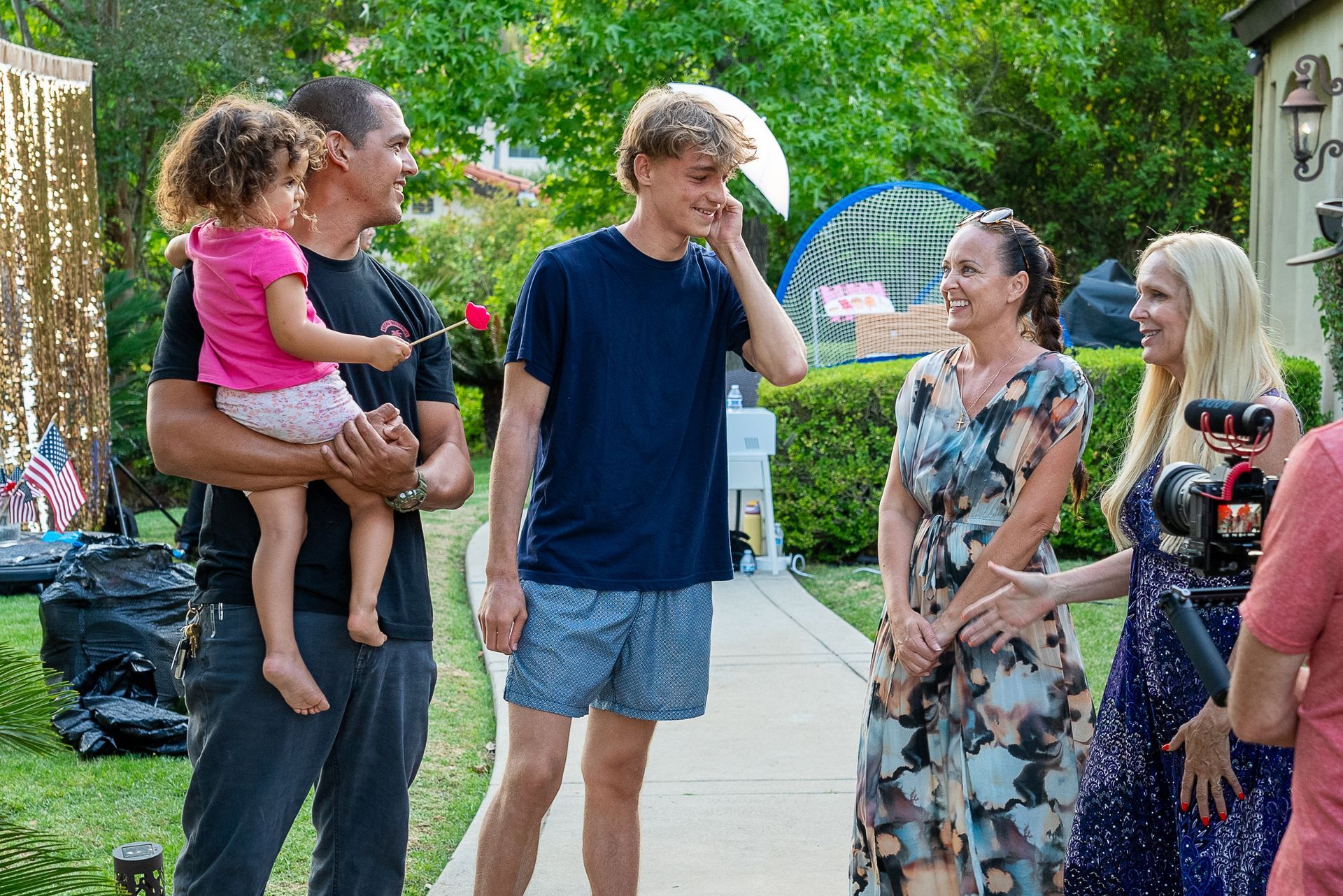 A group of people are standing on a sidewalk talking to each other.
