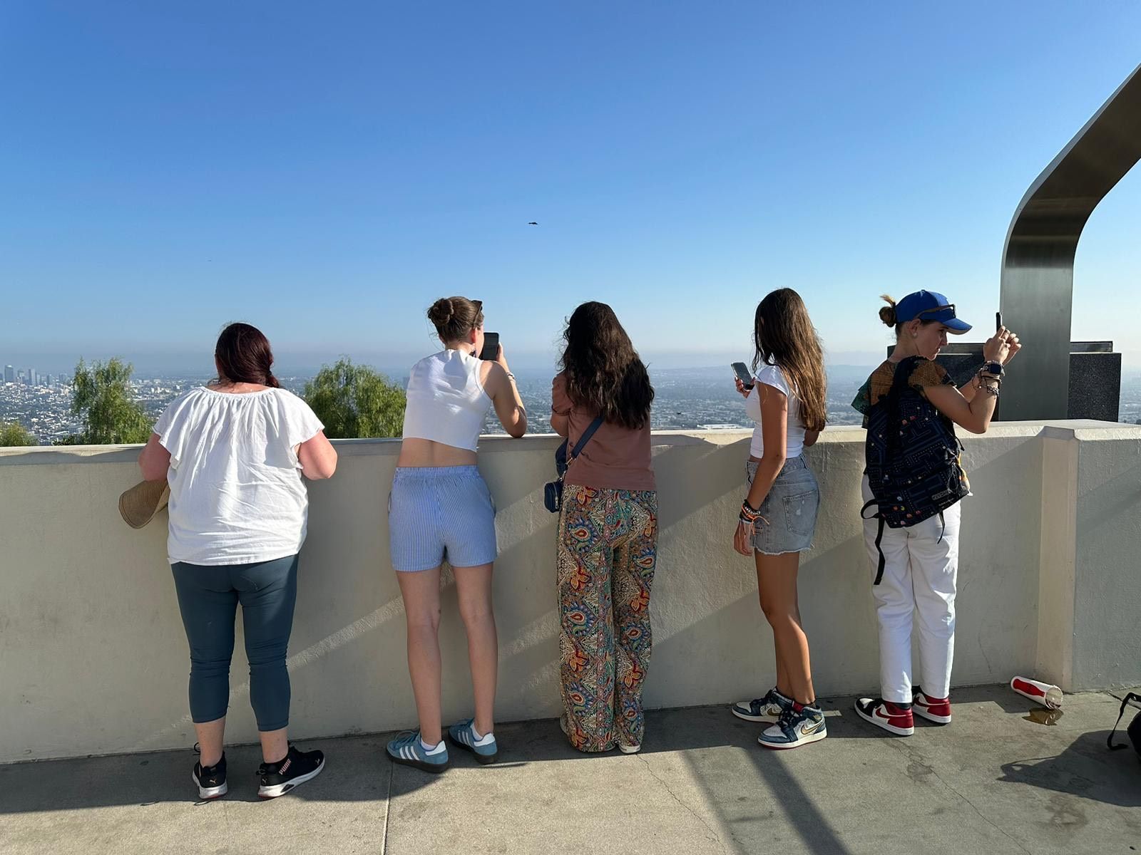 A group of people are standing on a balcony looking out over a city.