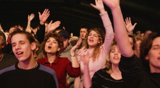 A crowd of people are raising their hands in the air at a concert.