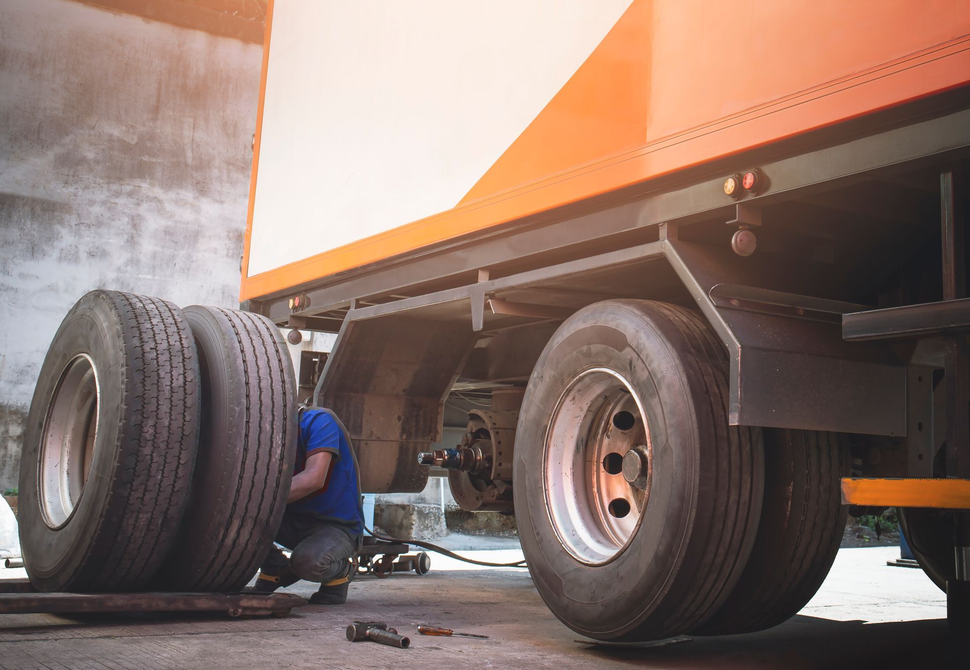 A man is changing a tire on a semi truck.