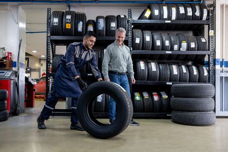 Two men are working on a tire in a garage. Two men are working on a tire in a garage.