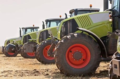 A row of tractors are parked in a field. A row of tractors are parked in a field.