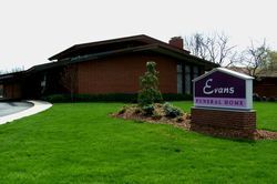 Evans Funeral Home sign beside a brick building and green lawn