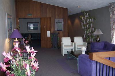 Lobby seating area with purple and white chairs, glass table, and floral arrangement