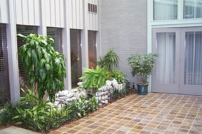 Courtyard patio with potted plants along a white building and brown tiled floor