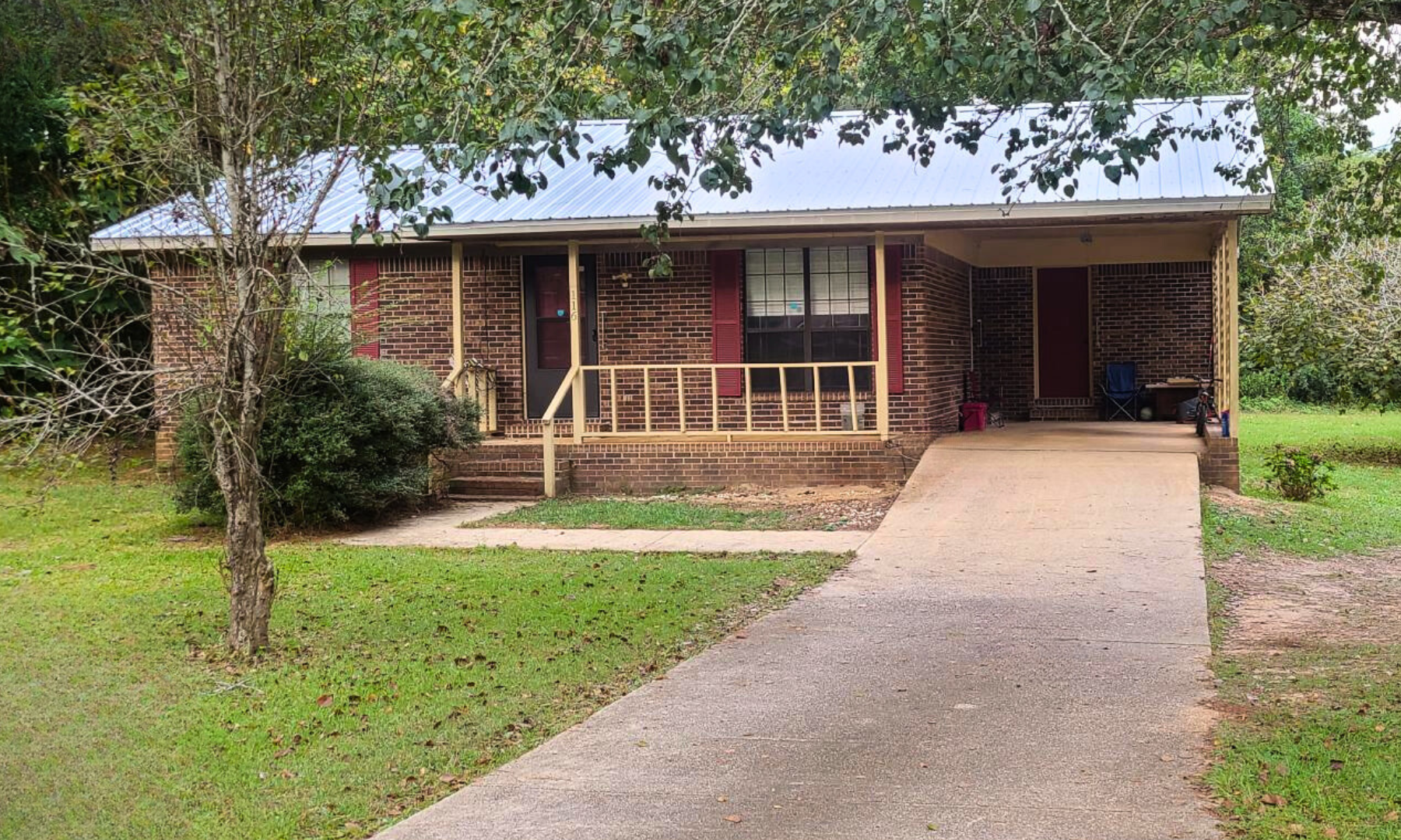 A brick house with a porch and a walkway leading to it.