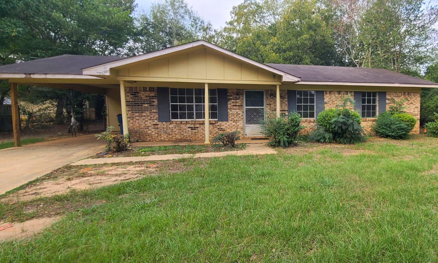 A brick house with a large lawn in front of it.