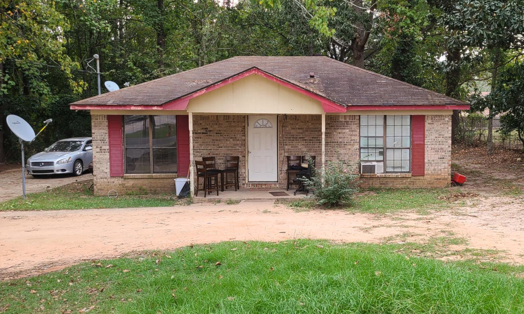 A small brick house with a car parked in front of it.
