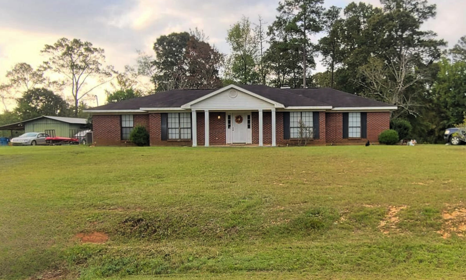 A large brick house is sitting in the middle of a lush green field.