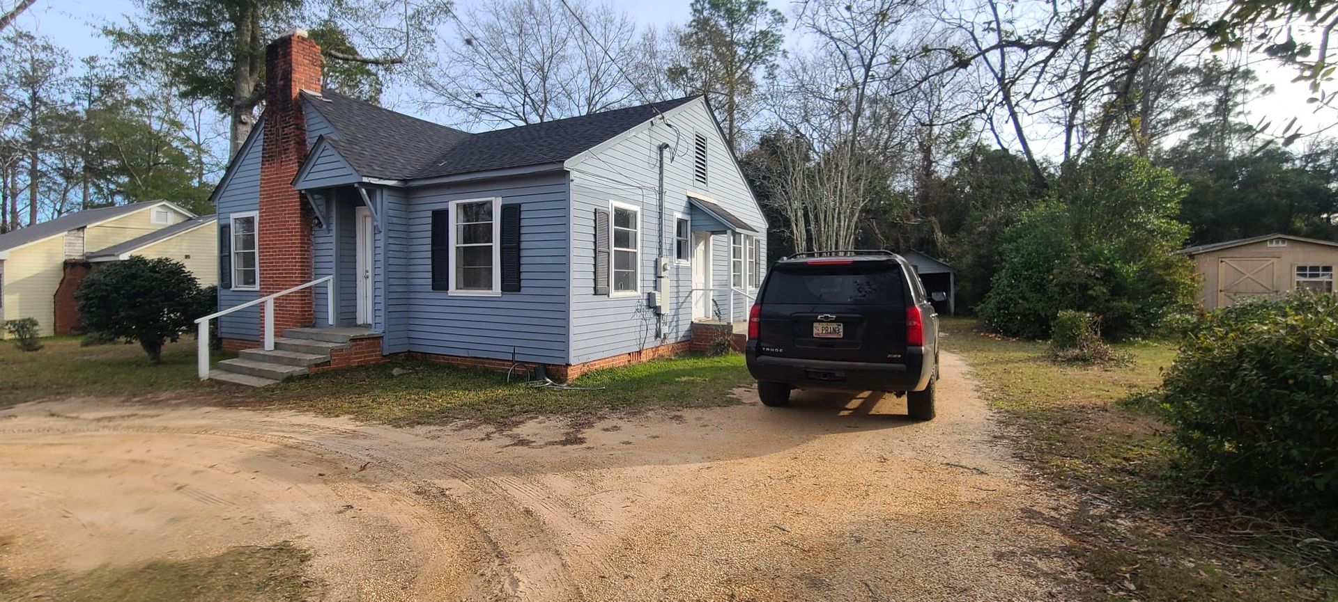 A blue house with a black suv parked in front of it.