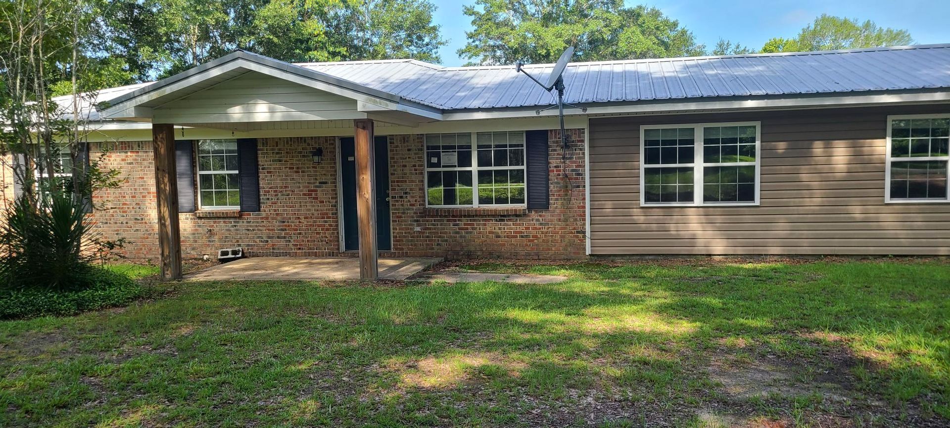 A brick house with a metal roof and a lot of windows is for sale.