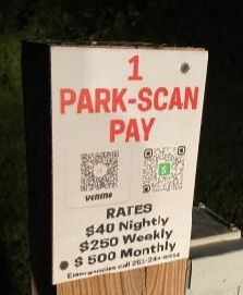 A sign that says `` park-scan pay '' is on a wooden post.