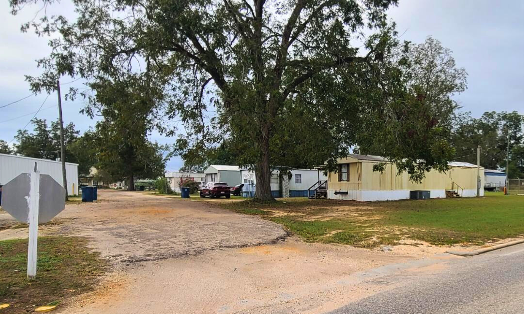 A group of mobile homes are parked on the side of a dirt road.