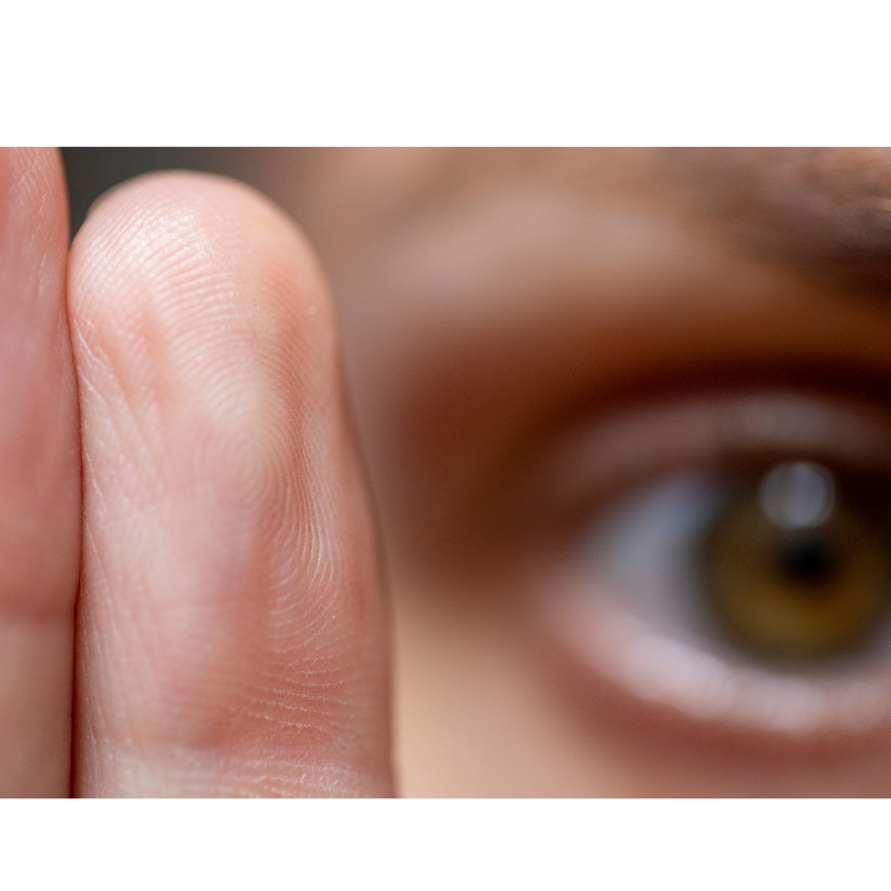 Close-up of a fingertip with fingerprint detail next to a blurred eye with hazel iris.