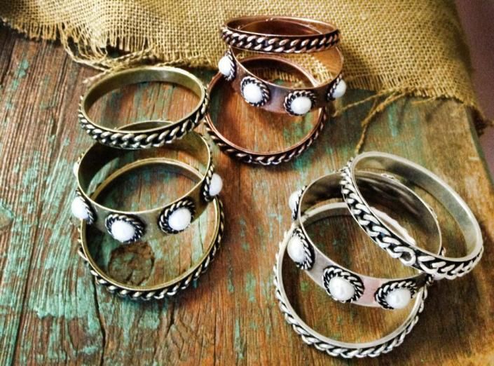 Assorted gold and silver metal bangles with white stone accents on a burlap background
