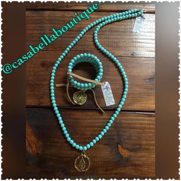 Turquoise beaded necklace with gold medallion and tassel on a wooden surface