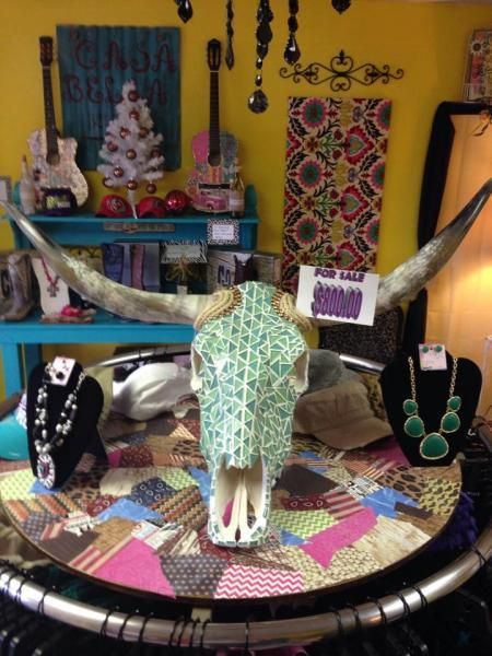Decorative horned skull centerpiece on a colorful table with jewelry displays in a shop.