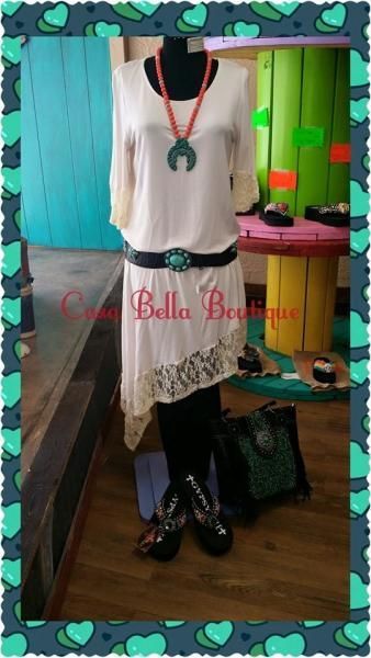Boutique display of a white dress with coral top, turquoise accents, black jewelry, and black shoes on a mannequin