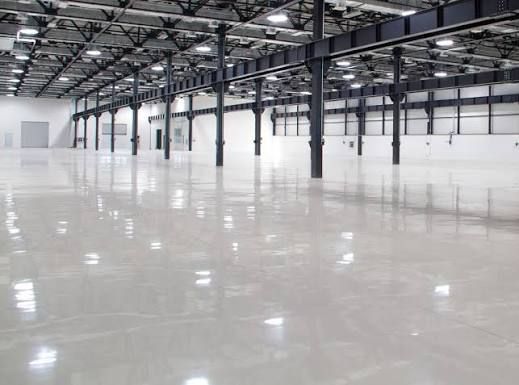 Empty warehouse interior with polished concrete floor and rows of metal support beams