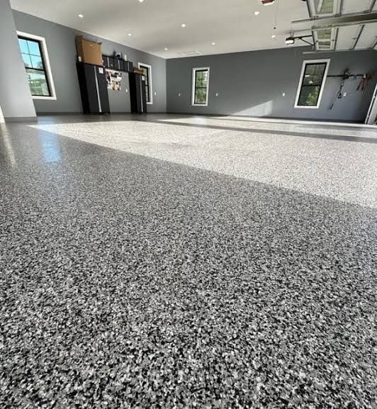 Empty gray garage with speckled epoxy floor and windows letting in daylight