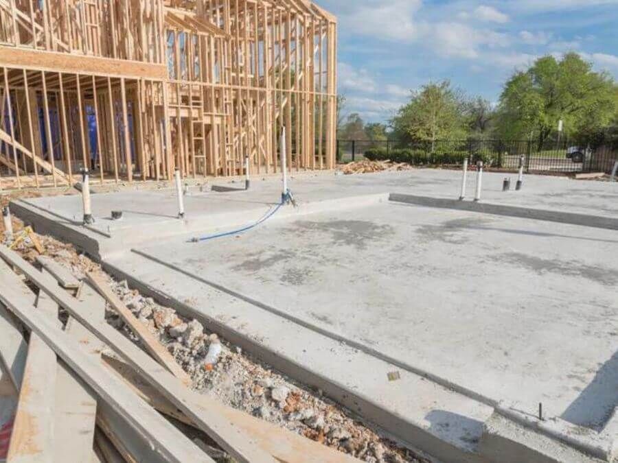 Concrete foundation slab at a house under construction beside wooden framing.