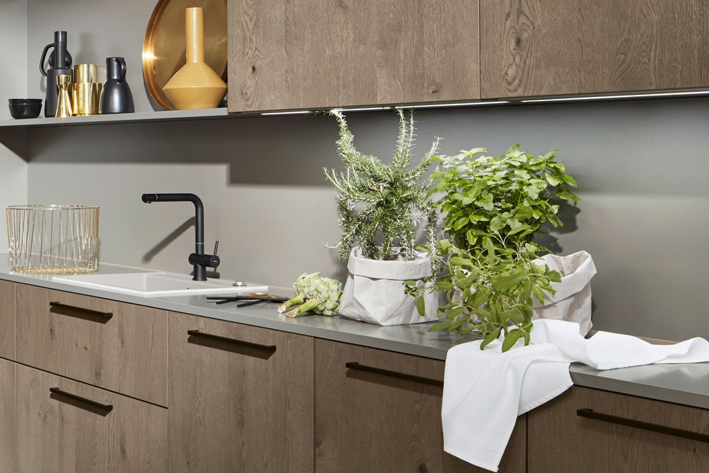 Une cuisine avec des armoires en bois et un évier avec des plantes sur le comptoir.