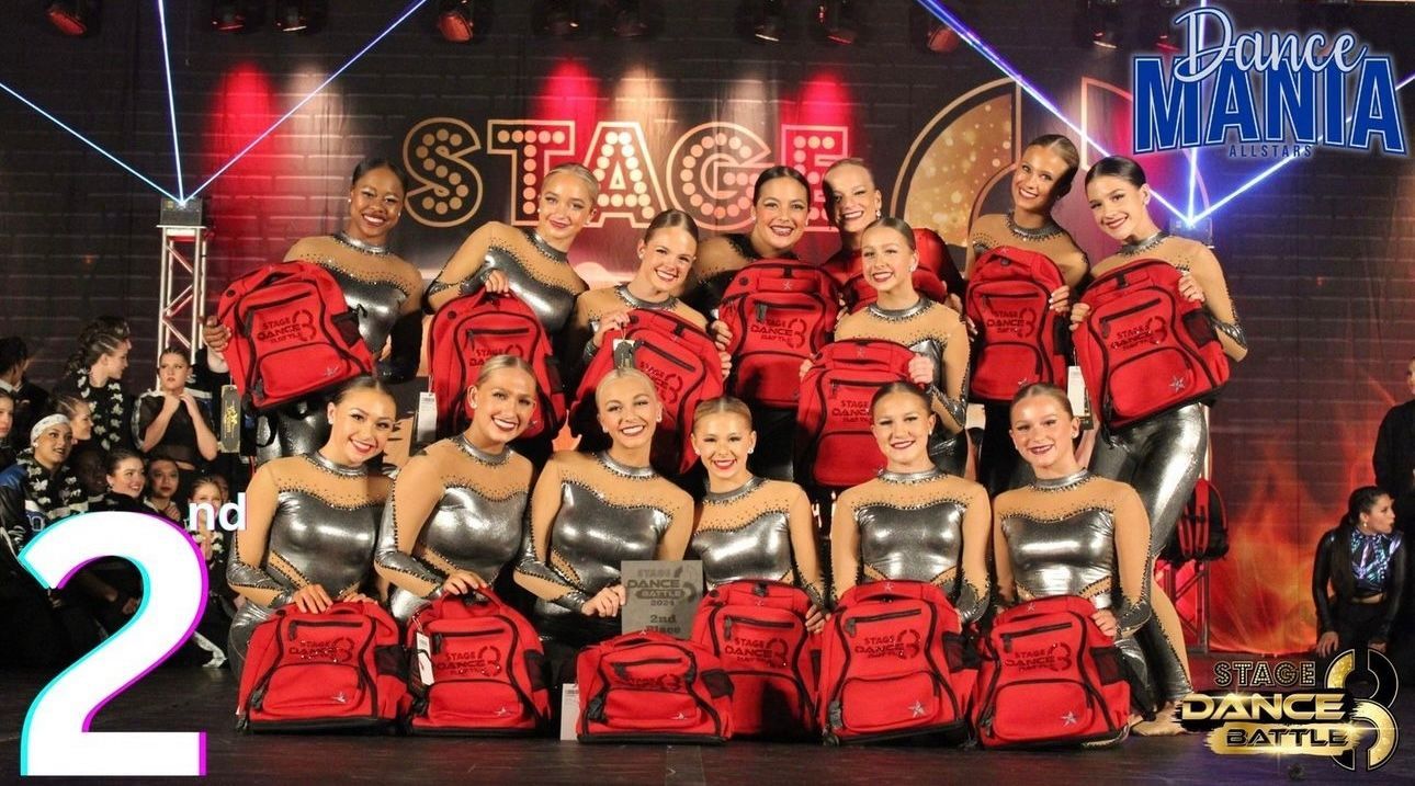 Dance team group in red-and-black costumes posing on a stage with a large “2” overlay.