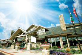 Modern lodge building with stone facade, flags, and bright sun in a blue sky