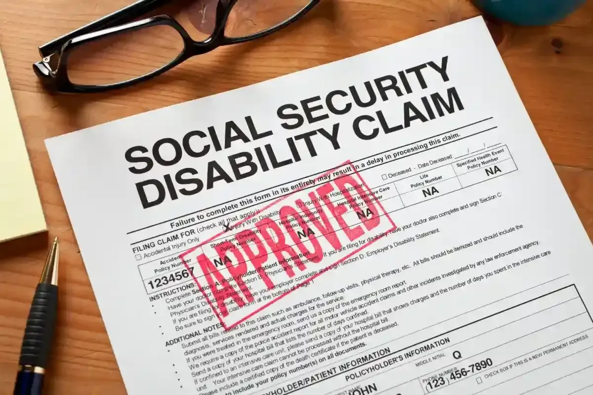 Approved Social Security Disability claim form on desk with glasses.