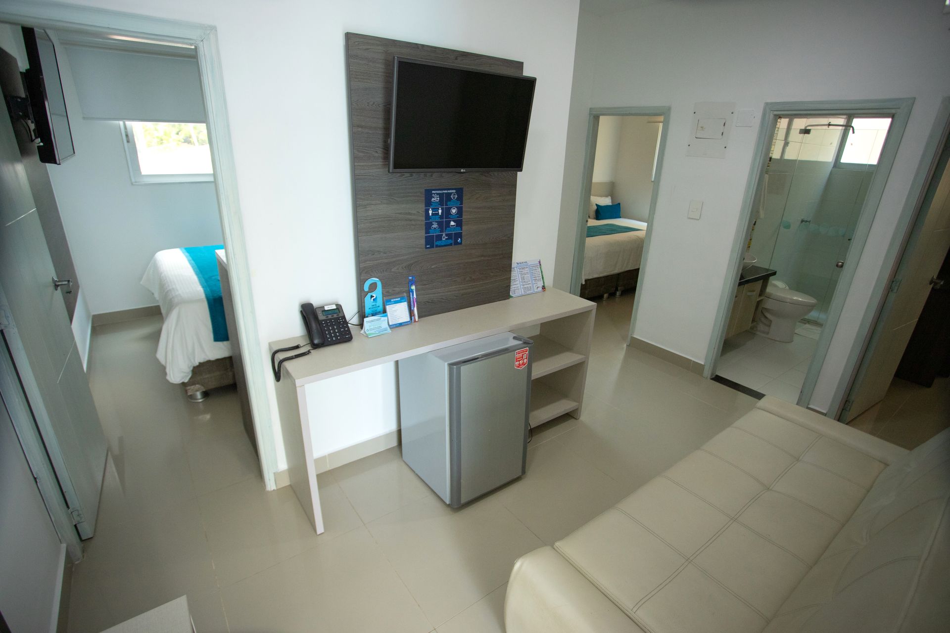 Modern hotel studio with TV, mini fridge, and seating area for your stay at a comfortable beach hotel in Coveñas