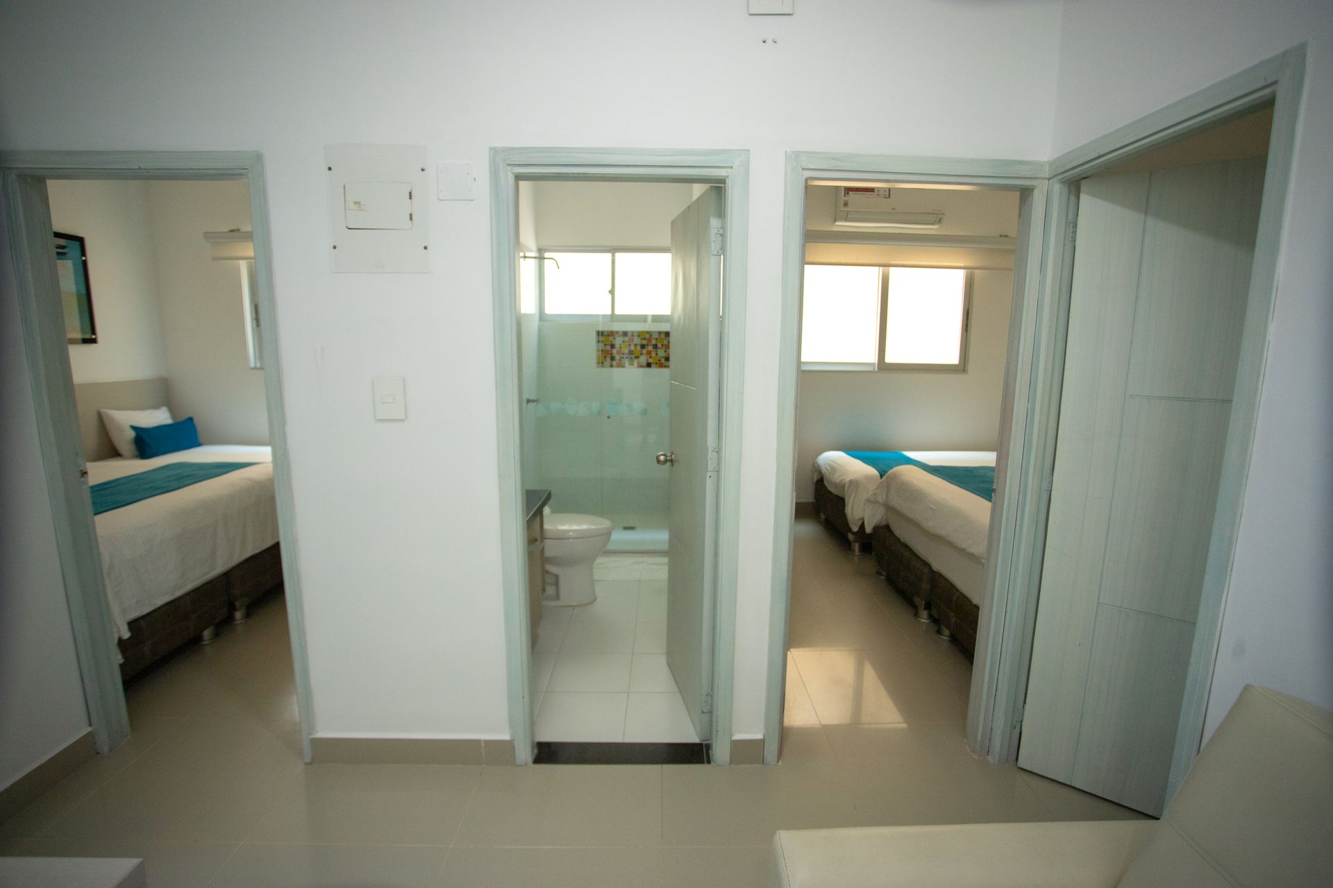 Multiple hotel rooms and a private bathroom inside a spacious suite at Hotel Poblado Coveñas