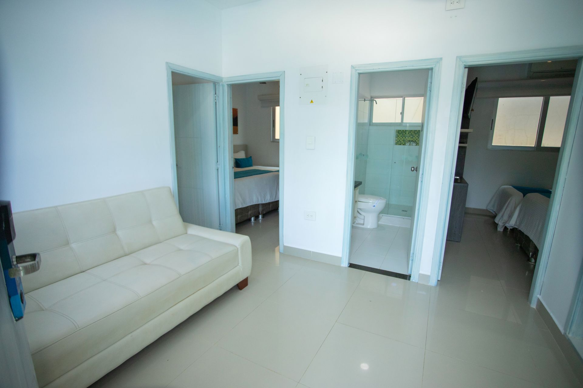 Spacious hotel in coveñas with a white leather sofa and open doors to bedrooms at Hotel Poblado Coveñas