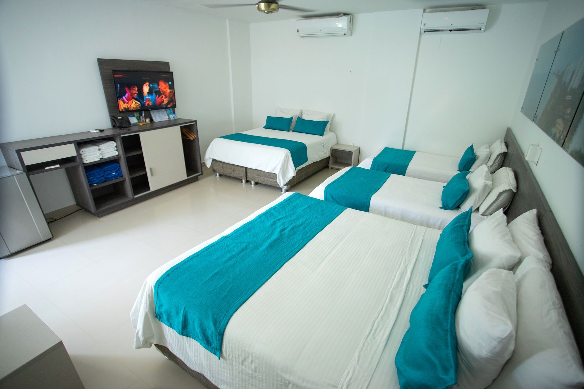 Large family room with multiple beds and TV for your group vacation at a comfortable hotel in Coveñas Colombia