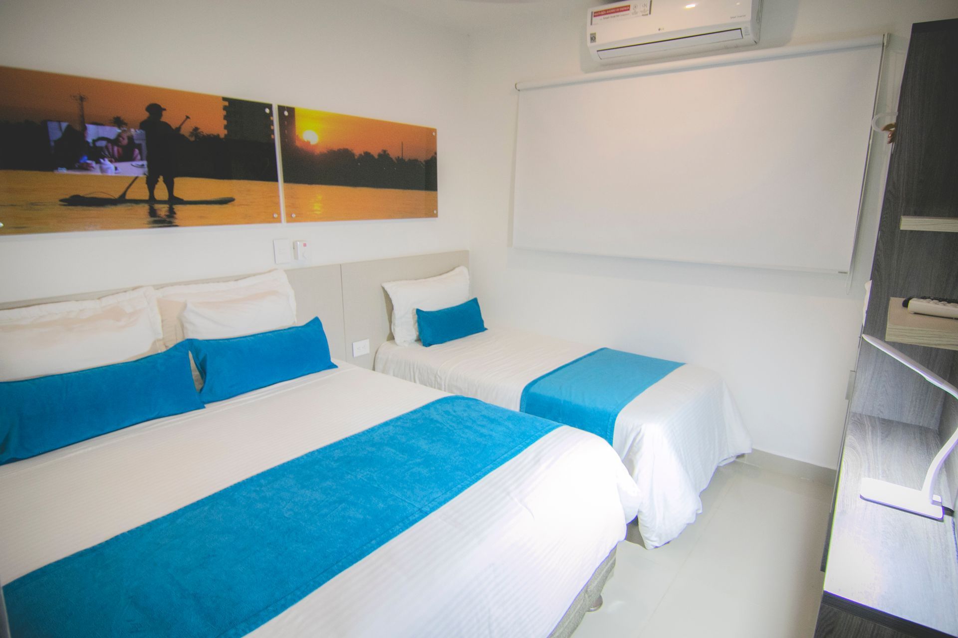 Room with multiple beds, air conditioning, and a projector screen for family trips at Hotel Poblado Coveñas